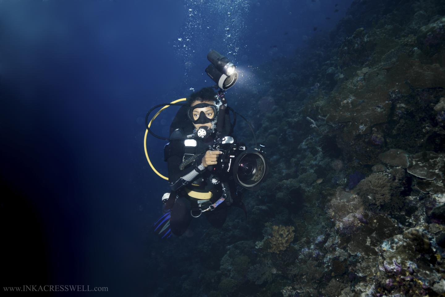 A underwater diver holds a camera